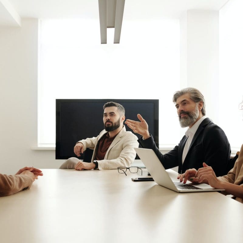 Man in Black Suit Jacket Sitting Beside Man in Black Suit
